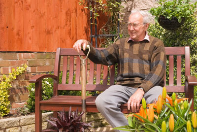 Senior sitzt auf einer Gartenbank